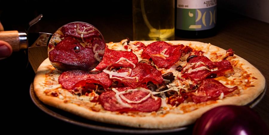 Pizza sendo fatiada à mesa