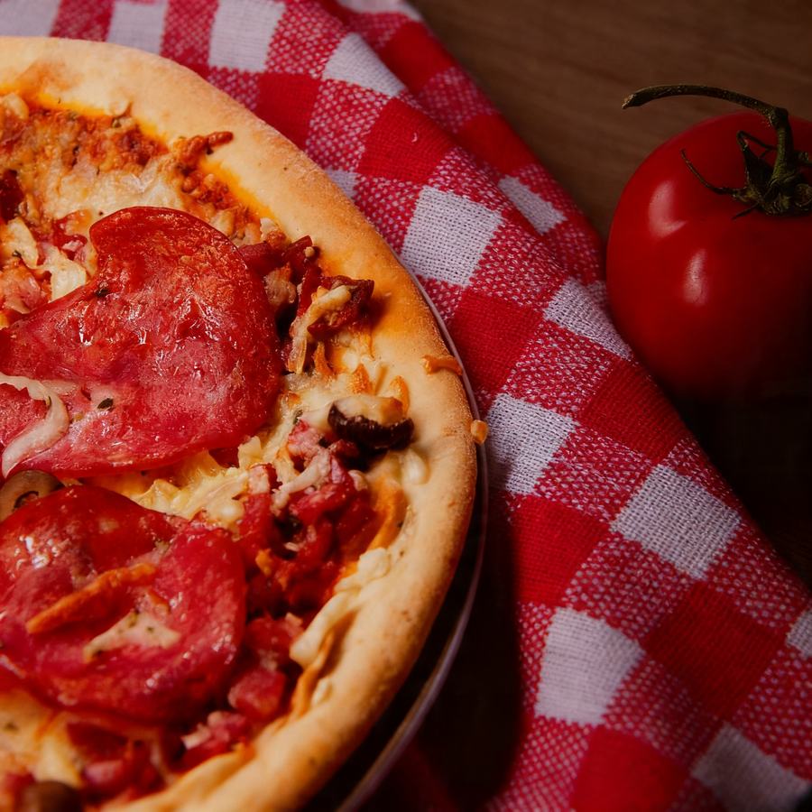 Pizza de calabresa servida sobre toalha xadrez